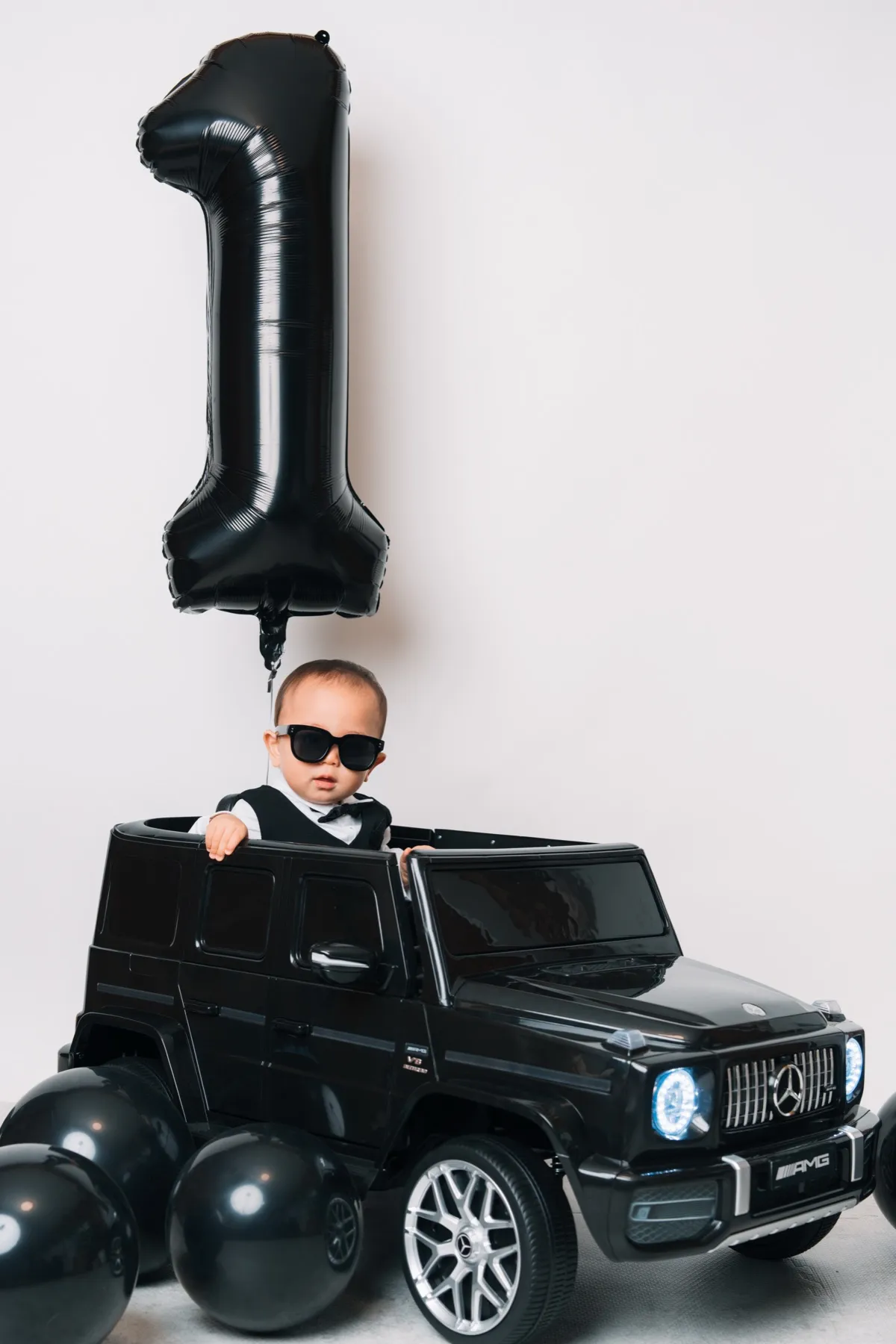 黒い数字バルーンとおもちゃの車でスタイリングしたクールな1歳記念写真