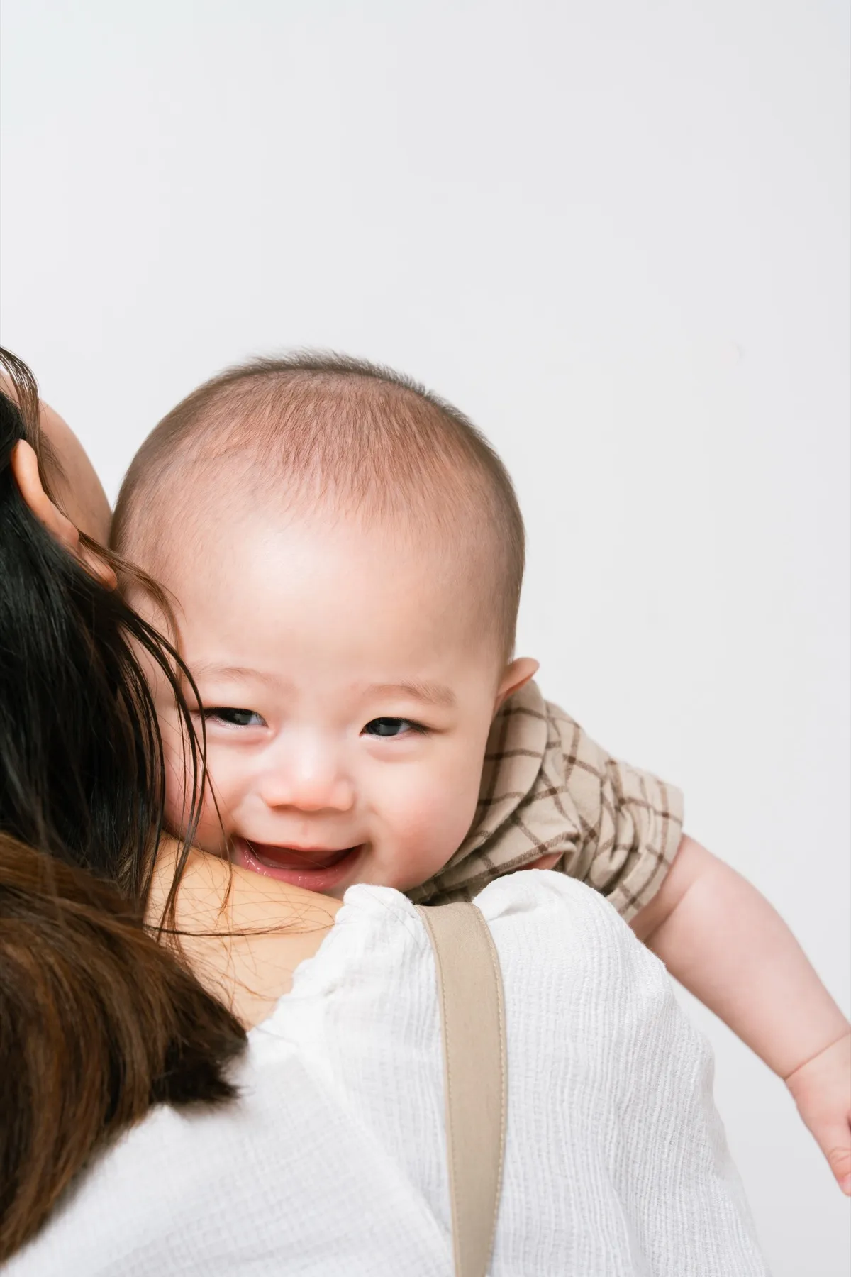 お母さまに抱っこされて振り返り笑顔を見せる赤ちゃん