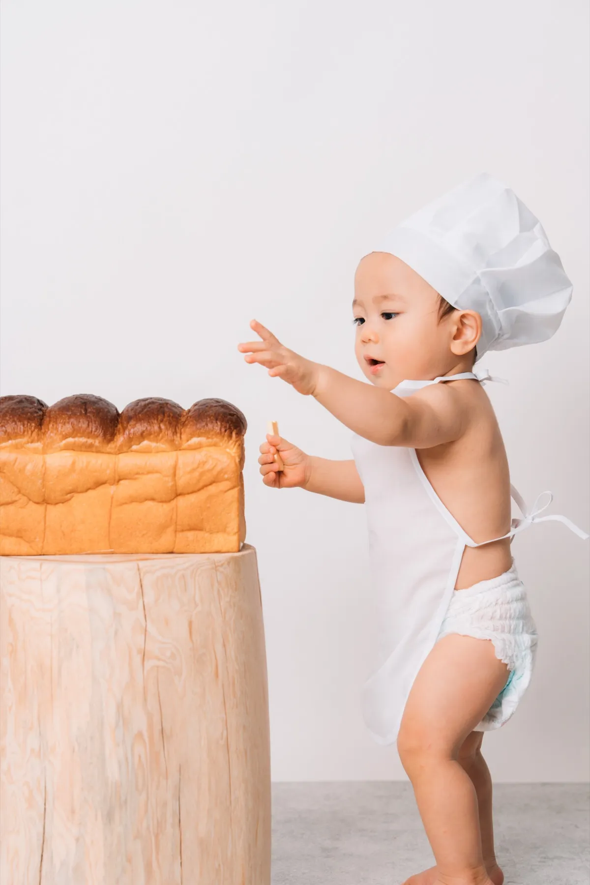 ベーカリー衣装で食パンを手づかみする赤ちゃん