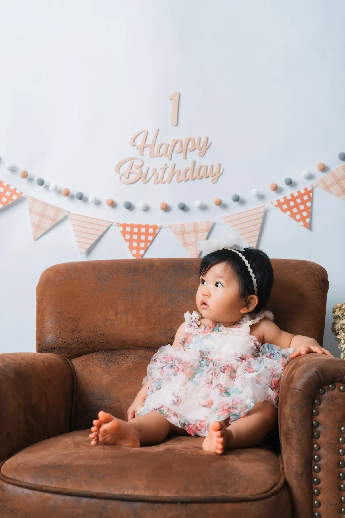 ヴィンテージのソファに座る、花柄ドレスの1歳の女の子